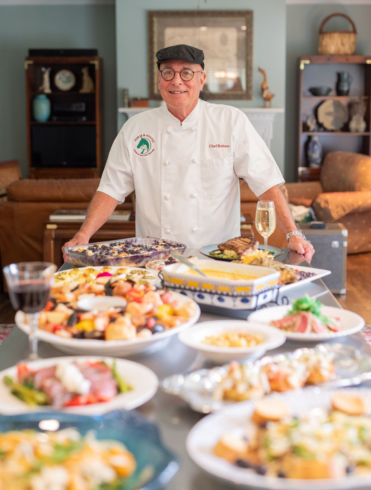 Chef Robert Atchison in his Horse and Hound chef jacket, standing behind a spread of catered dishes